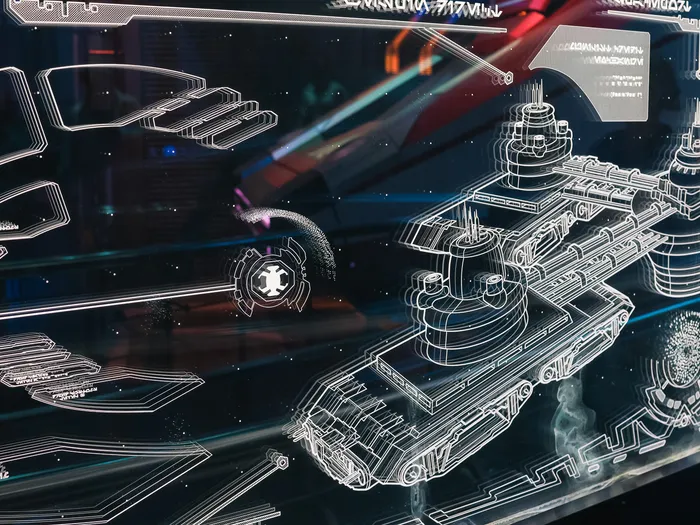 Schémas holographiques de vaisseaux tracés en lignes lumineuses sur un panneau sombre dans la file d'attente de Star Tours