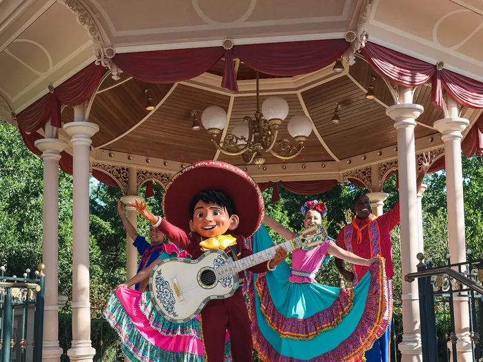 Miguel, guitar in hand, surrounded by dancers in colourful dresses in the bandstand, Miguel’s Fiesta Latina show at Disneyland Paris