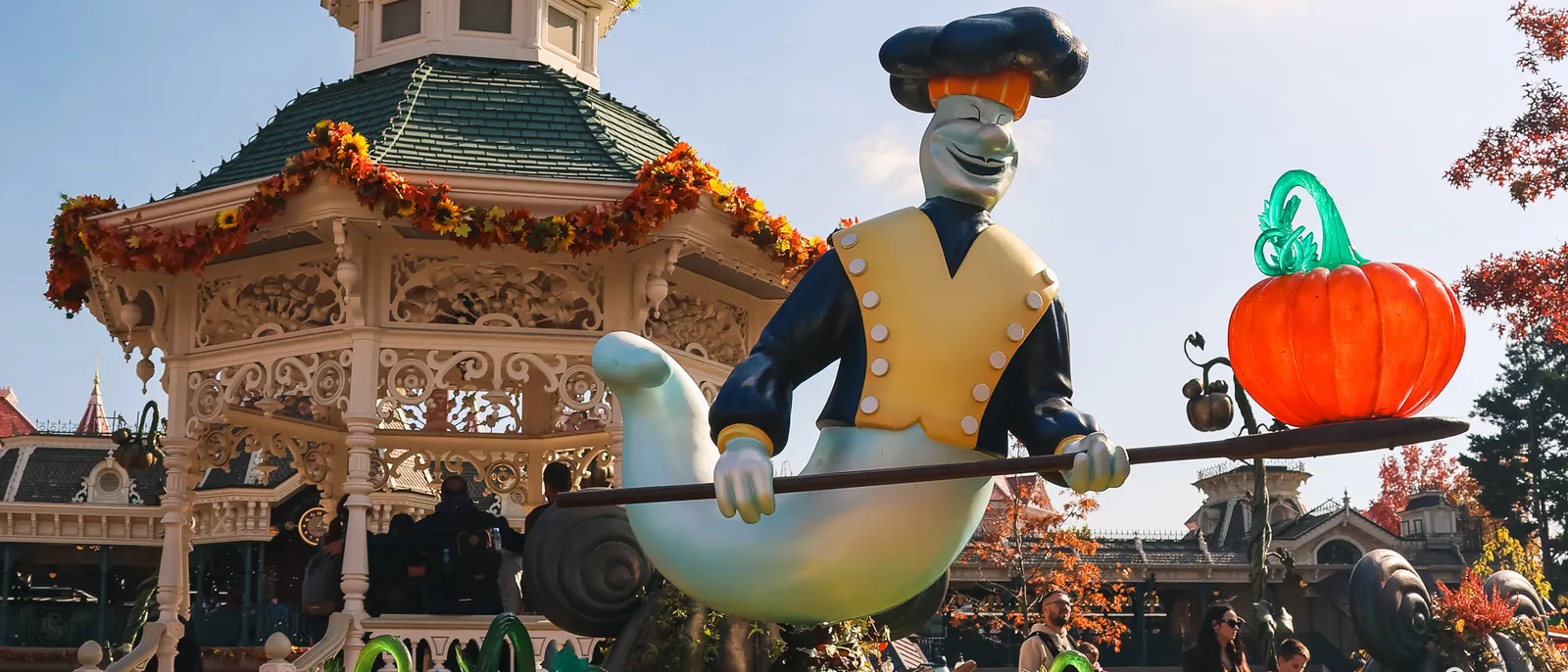 Grande figure décorative d’Halloween et citrouille orange devant le kiosque à musique fleuri de Main Street.