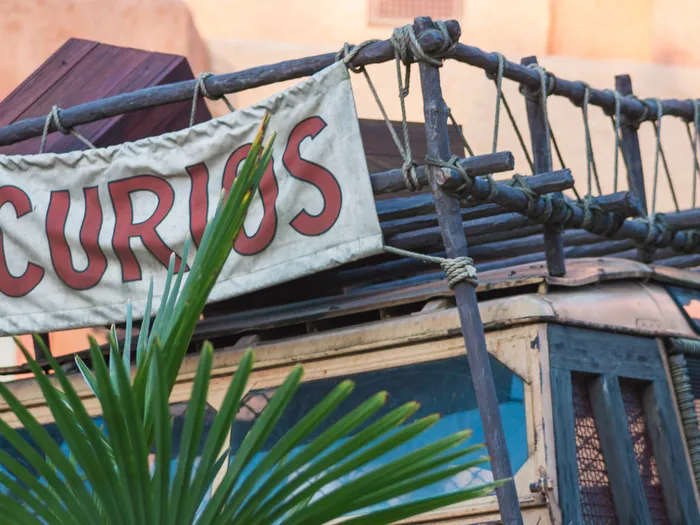 Banderole « Curios » tendue au-dessus d’un vieux camion en bois, dans le décor d’Adventureland.