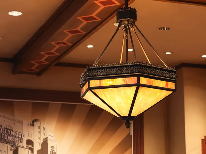 Art Deco pendant light in amber glass and black metal in the Tower Hotel Gifts shop, Disneyland Paris, before a Hollywood Tower Hotel mural