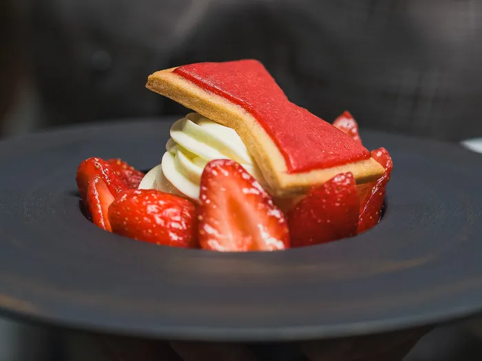 Dessert aux fraises, sablé et crème, servi sur une assiette noire au Manhattan Restaurant