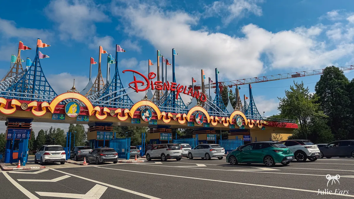 Disneyland Paris car park toll booths: red "Disneyland" sign, blue pennant structures and medallions of Aurora, Mickey, Minnie and Buzz Lightyear