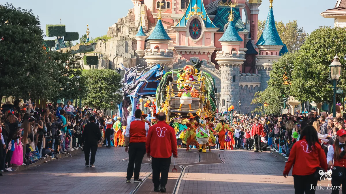 Halloween parade on Main Street U.S.A. in front of Sleeping Beauty Castle, Disneyland Paris: Daisy leads the float of Donald, José Carioca and Panchito between packed crowds
