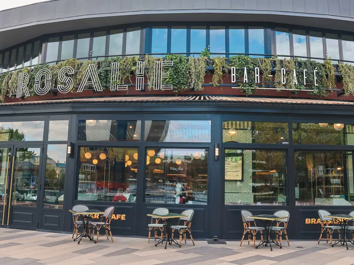 Façade arrondie de la Brasserie Rosalie avec terrasse et chaises bistrot au Disney Village