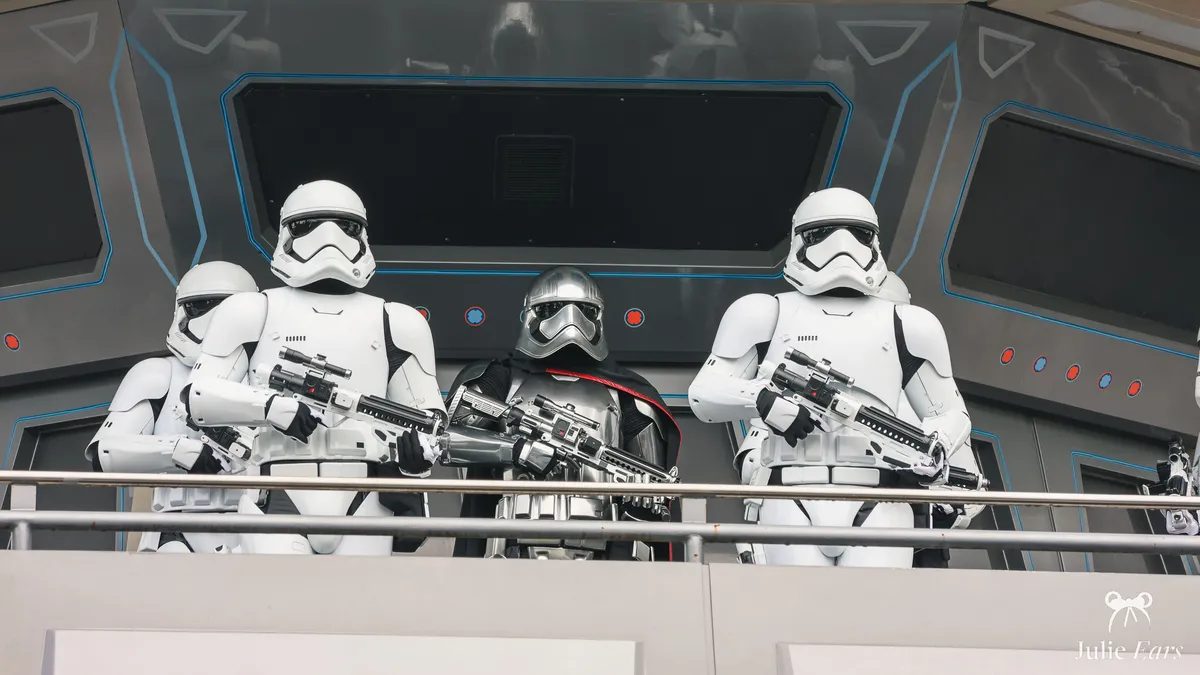 Captain Phasma in chrome armour and a black cape, with First Order Stormtroopers holding blasters on a Discoveryland balcony, Disneyland Paris