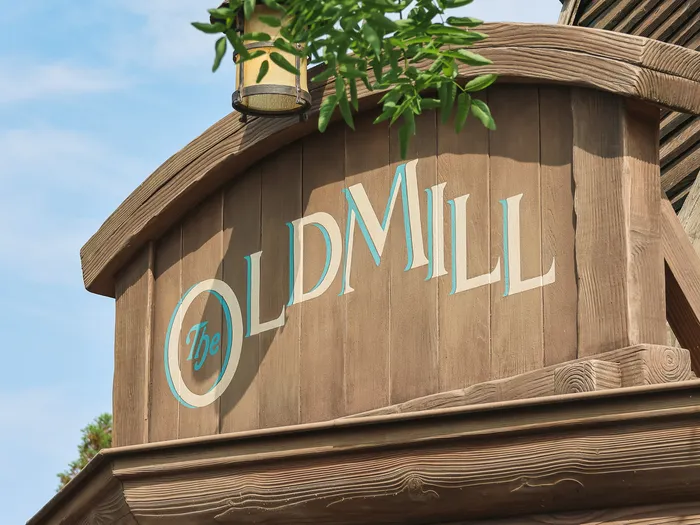 Enseigne bleue et bois gravée The Old Mill sur la façade du moulin du restaurant à Fantasyland