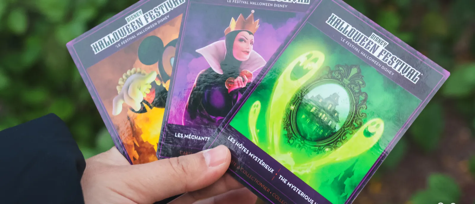 Trois cartes collector du Disney Halloween Festival tenues en éventail à Disneyland Paris, dont la Reine sorcière.