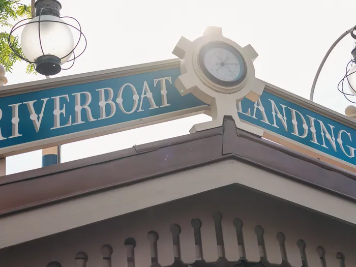 Enseigne bleue Riverboat Landing surmontée d’une horloge et de deux lanternes à l’embarcadère Thunder Mesa Riverboat Landing