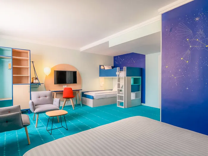 Chambre familiale du Grand Magic Hotel avec lits superposés, fresque étoilée et moquette turquoise.