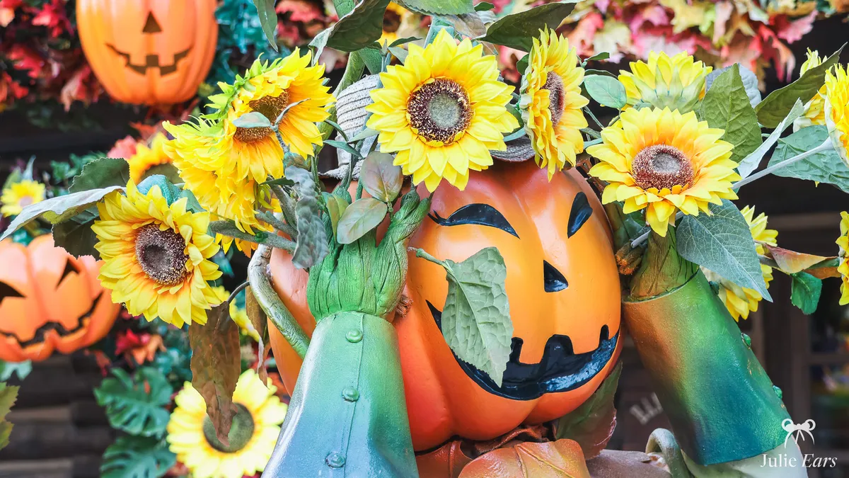 Large carved Halloween pumpkin, surrounded by sunflowers and autumn foliage, at Disneyland Paris