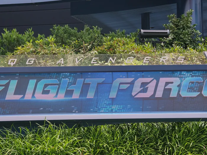 Enseigne lumineuse « Flight Force » et « QG Avengers » de l’attraction, encadrée de plantations à Avengers Campus.