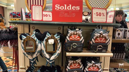 Star Wars Ahsoka backpacks and ear headbands on display under large red 50% off posters at Disneyland Paris.