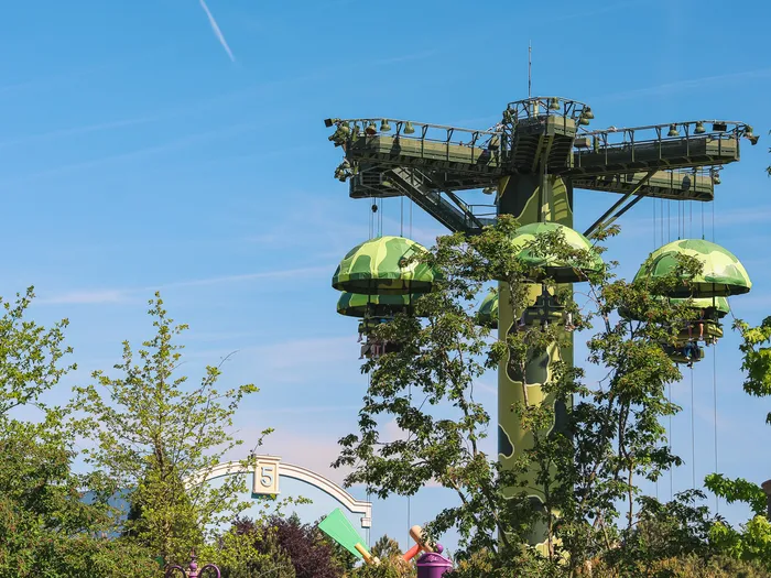 Trois nacelles-parachutes vertes suspendues à la tour de Toy Soldiers Parachute Drop à Worlds of Pixar, sous un ciel bleu.