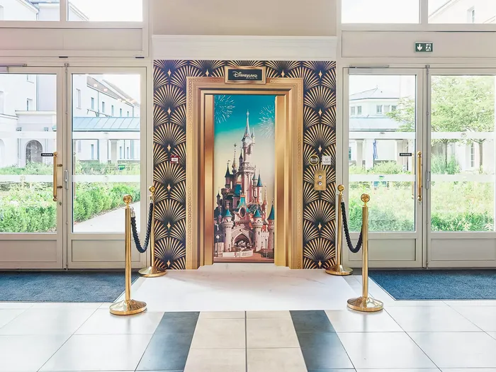 Hall du B&B Hôtel près de Disney avec décor photo du château Disneyland et cordons dorés
