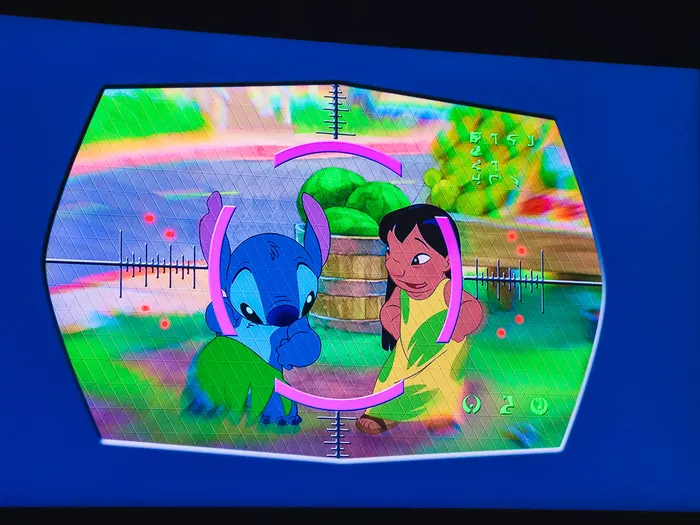 Écran bleu de Stitch Live avec Stitch et Lilo cadrés dans un réticule rose, sur fond de jardin verdoyant.