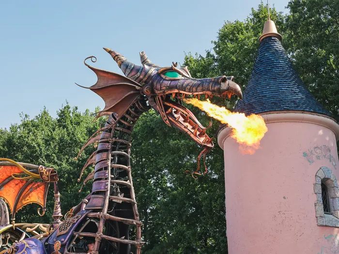 Char dragon de Maléfique crachant du feu près d’une tourelle rose pendant la parade Disney Stars on Parade