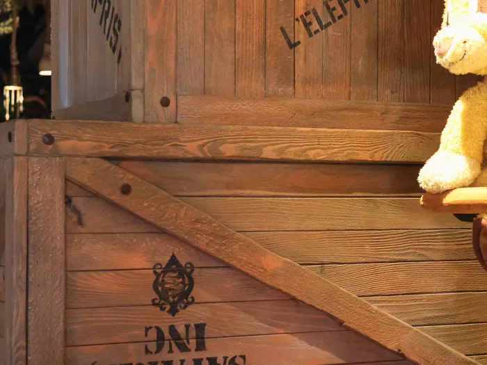 Wooden crates painted with "Sligo Safaris Inc" and French words for elephant porcelain, with a lion cub soft toy, in La Girafe Curieuse