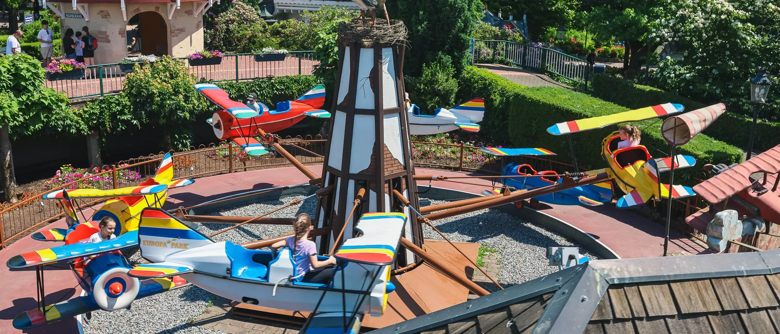 Manège d’avions colorés tournant autour d’un moulin, avec des enfants à bord, à Europa-Park.