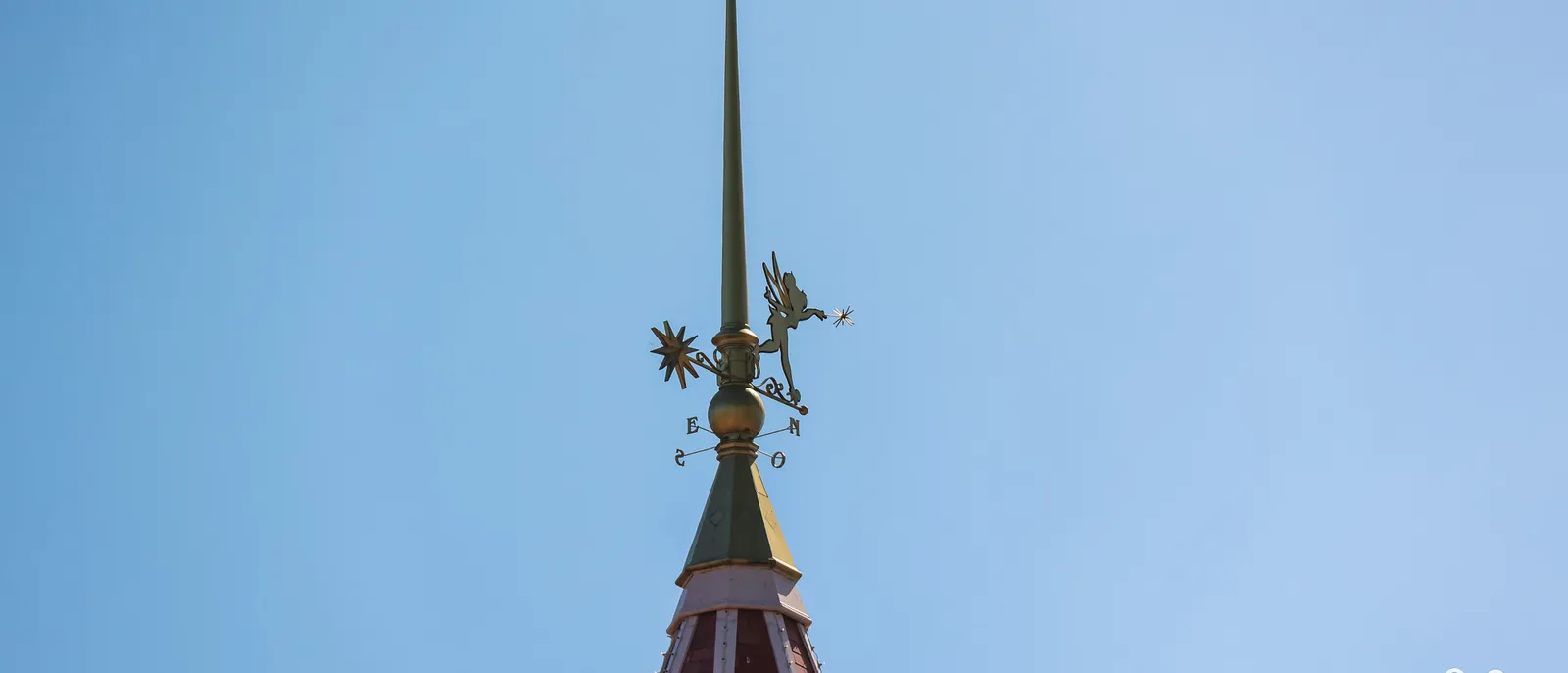 Girouette dorée de la Fée Clochette au sommet d’une flèche du Disneyland Hotel, sur ciel bleu