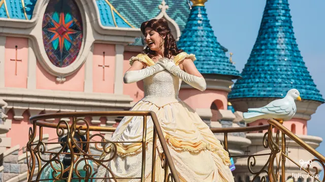 La princesse Belle, dans sa robe jaune de bal, sur un char devant le château à Disneyland Paris.
