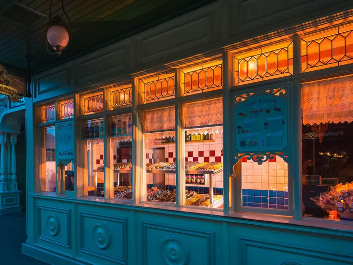 Les vitrines éclairées de la Cookie Kitchen, garnies de pâtisseries, à la tombée du jour sur Main Street USA.