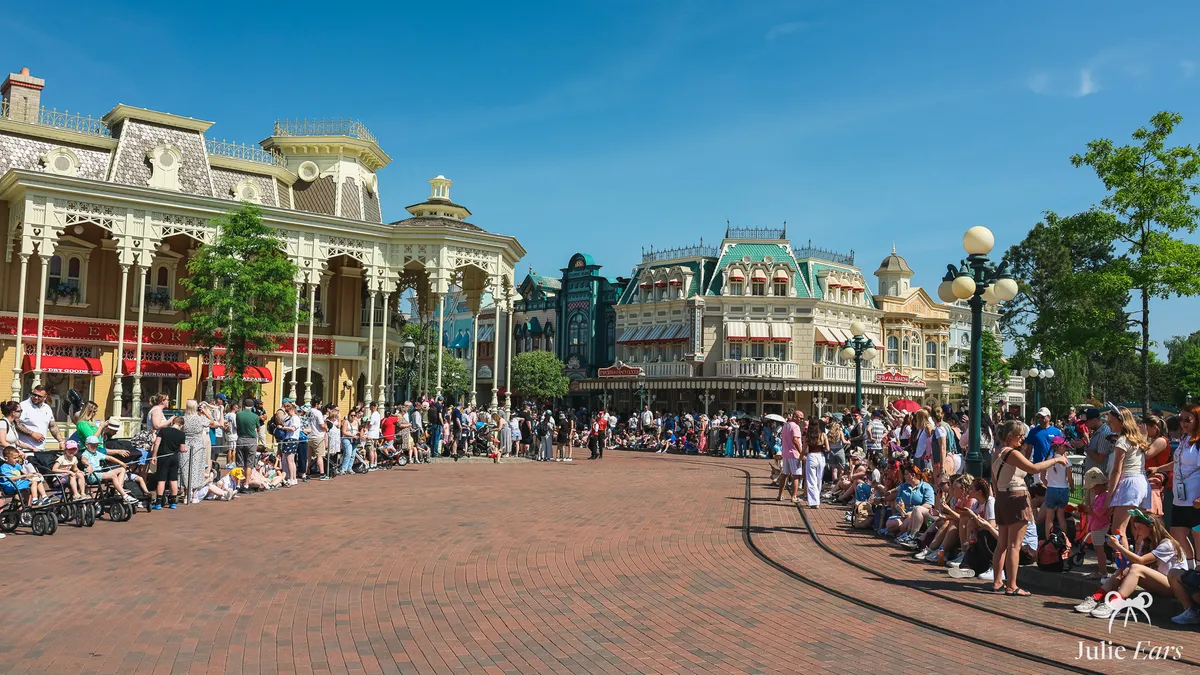 Visitors lining the pavements of Town Square at the start of Main Street U.S.A., waiting for the parade on a sunny day at Disneyland Paris