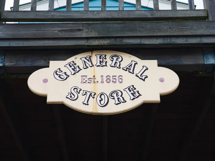 Close-up of the oval "General Store, Est. 1856" sign fixed between wooden beams.