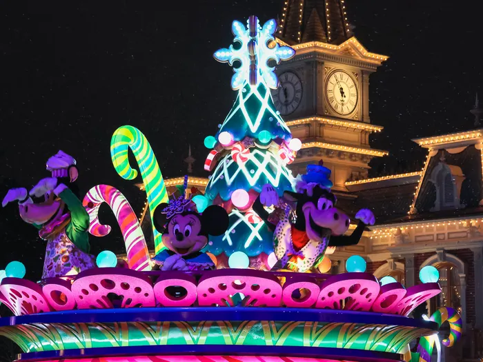 Char illuminé avec Mickey et Minnie devant l’horloge de Main Street pendant la parade de Noël nocturne.