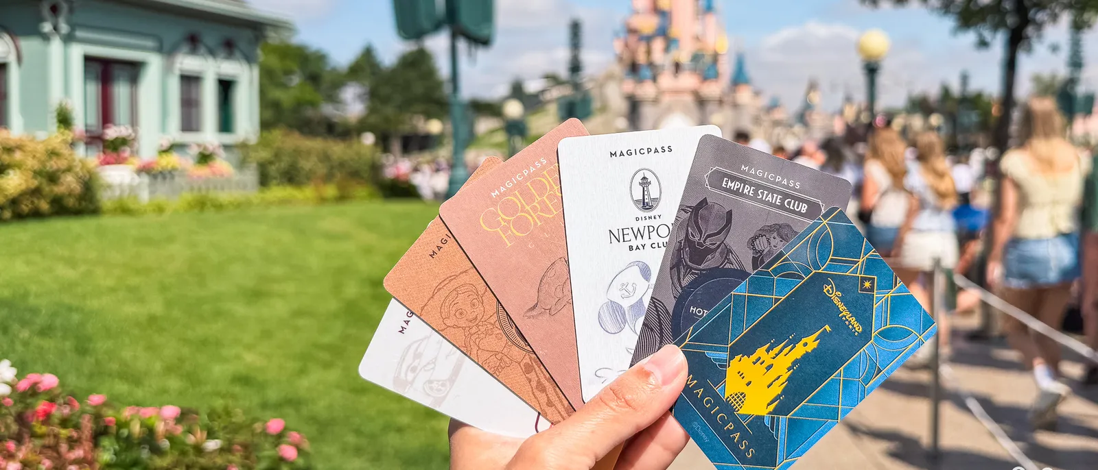 Cartes Magic Pass des hôtels Disney tenues en éventail devant le château de Disneyland Paris