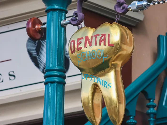Tooth-shaped gold "Dental School Upstairs" sign, a Main Street U.S.A. gag