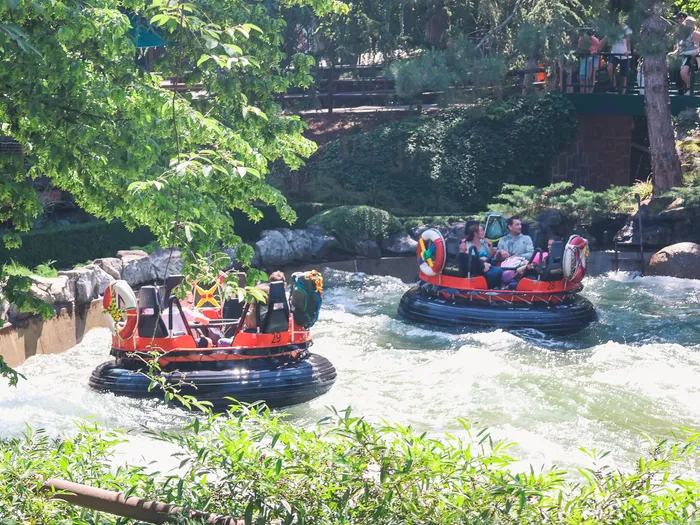 Bouées rondes chargées de visiteurs descendant une rivière de rapides bordée d’arbres à Europa-Park.