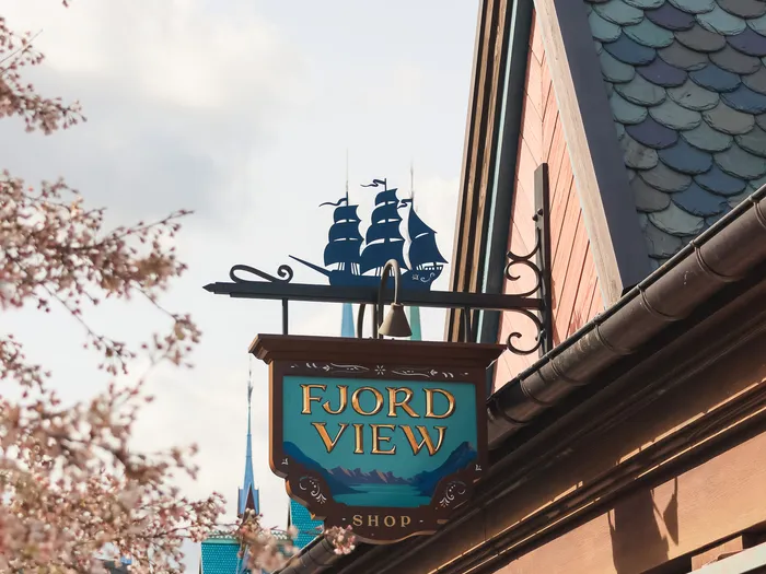 Fjord View Shop sign topped with a sailing boat, surrounded by cherry trees in blossom at Disneyland Paris