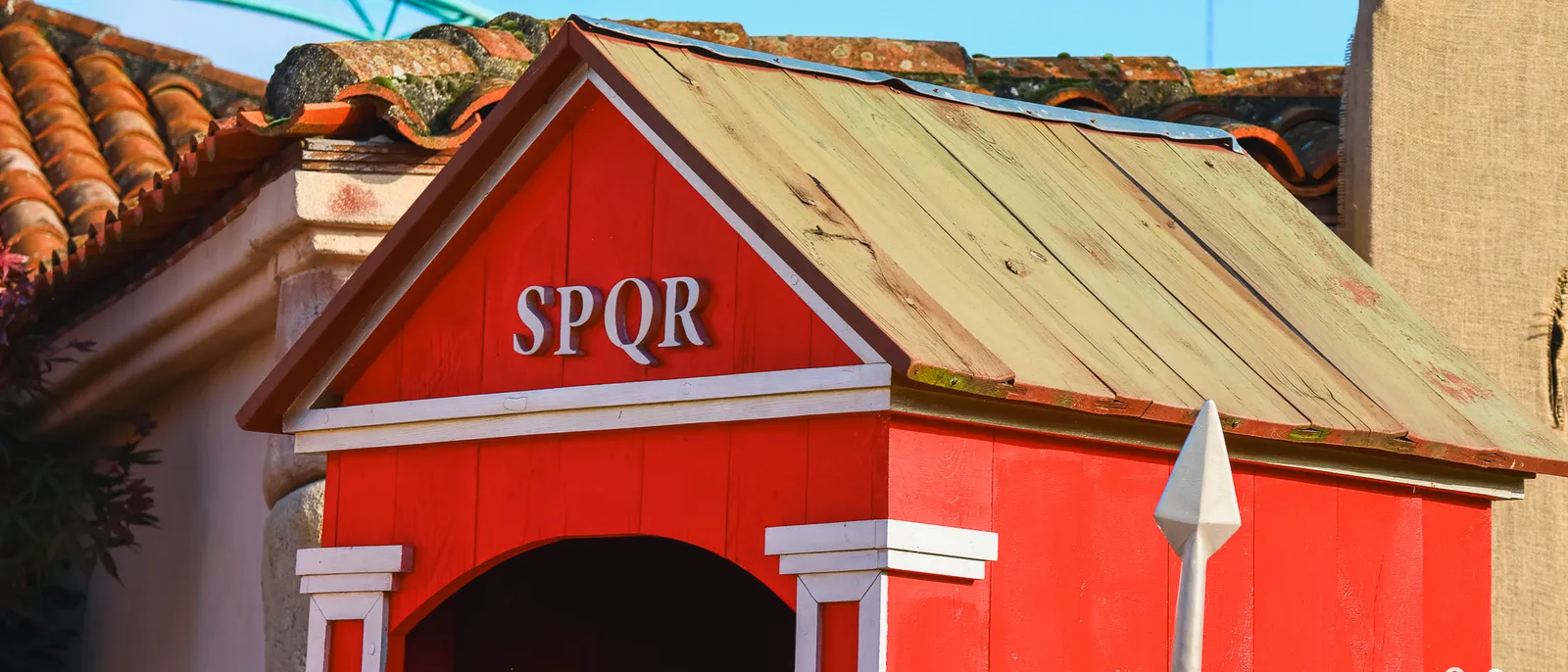 Guérite rouge marquée SPQR sur son fronton, toit de planches et de tuiles romaines, lance plantée devant