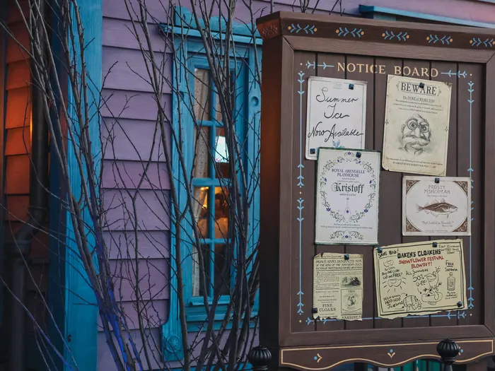 Panneau d’affichage thématisé Arendelle couvert d’avis, sur la façade colorée du restaurant Nordic Crowns Tavern