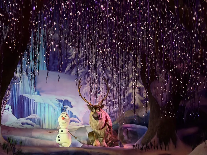 Olaf et le renne Sven réunis dans une forêt enneigée scintillante de lumières violettes, scène de Frozen Ever After.