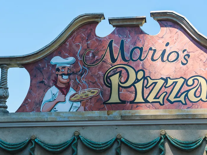 Enseigne Mario’s Pizza illustrée d’un pizzaïolo, sur fond de ciel bleu, à Europa-Park