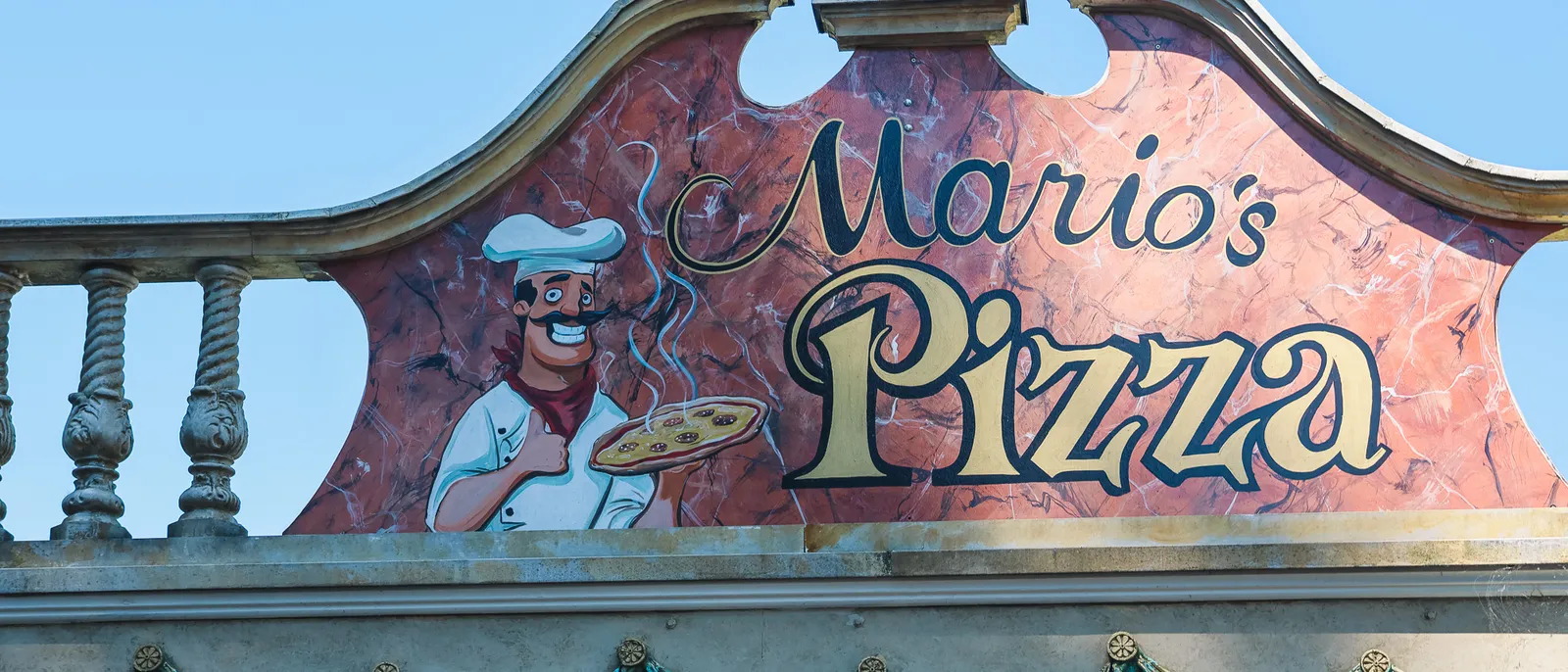Enseigne Mario’s Pizza illustrée d’un pizzaïolo, sur fond de ciel bleu, à Europa-Park