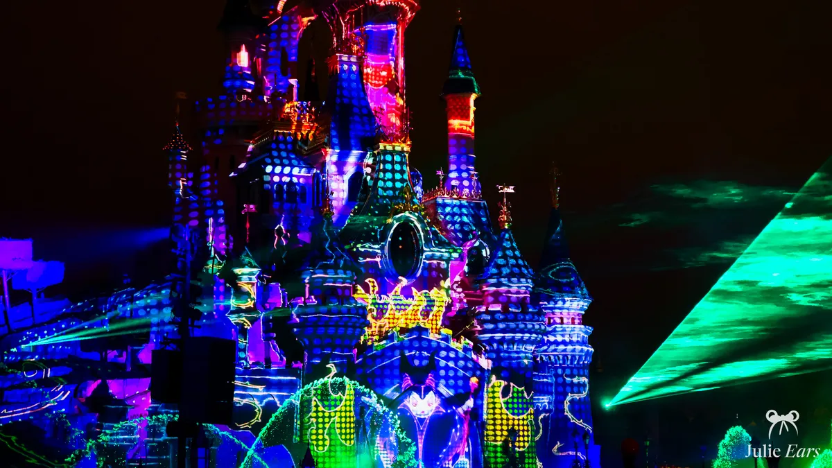 Sleeping Beauty Castle lit up with projections and colourful lasers during a night-time show at the Halloween party at Disneyland Paris
