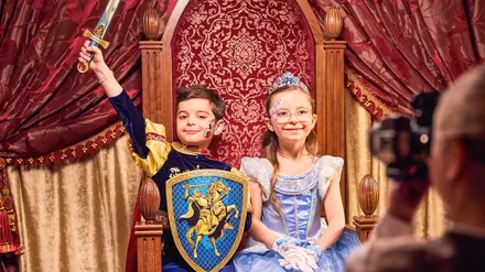 Séance photo de l’expérience Mon Rêve Royal au Disneyland Hotel : deux enfants costumés en prince et princesse sur un trône