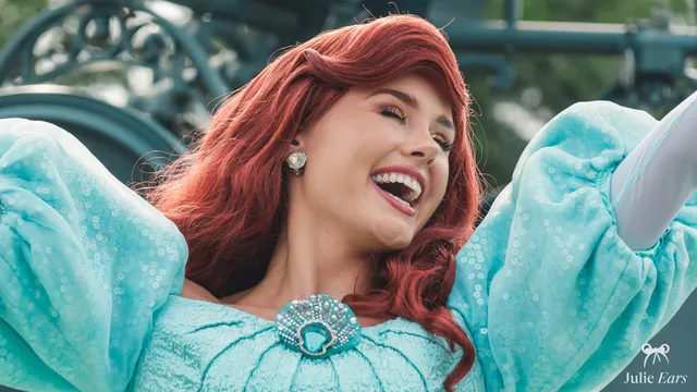 La princesse Ariel, chevelure rousse et robe turquoise à paillettes, rit lors de la parade à Disneyland Paris.