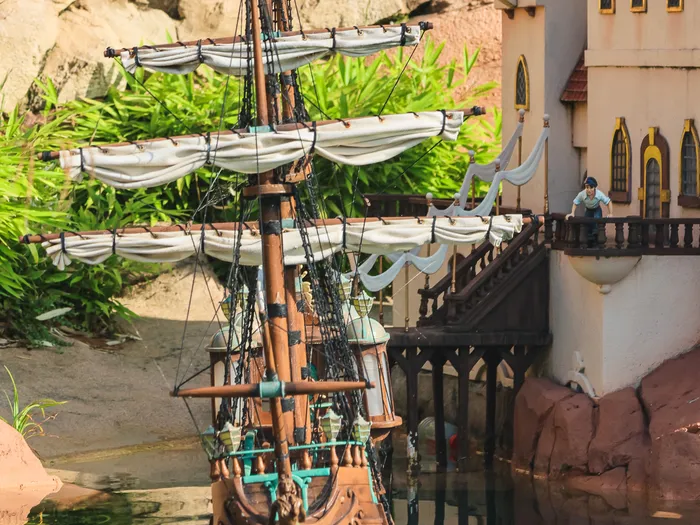 Miniature d’un galion à voiles amarré près d’un palais de conte au bord de l’eau, au Pays des Contes de Fées à Fantasyland