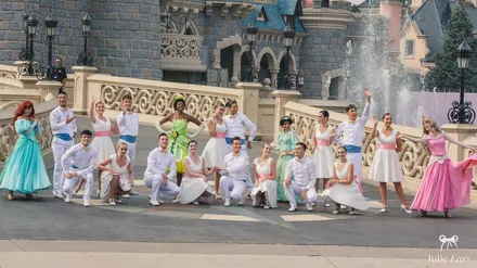 The princess celebration cast (Ariel, Tiana, Jasmine, Aurora) and dancers posing before the castle during World Princess Week at Disneyland Paris