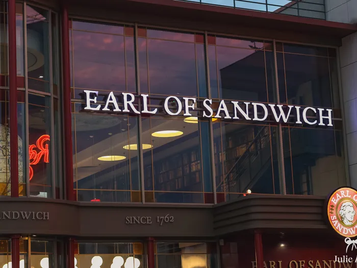 Enseigne lumineuse Earl of Sandwich sur la baie vitrée du restaurant au crépuscule à Disney Village