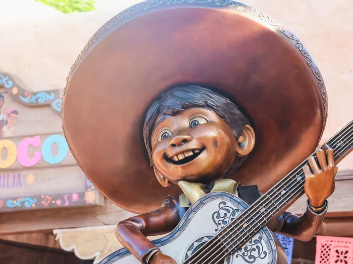 Statue de Miguel coiffé d'un sombrero et jouant de la guitare devant l'enseigne du restaurant Casa de Coco