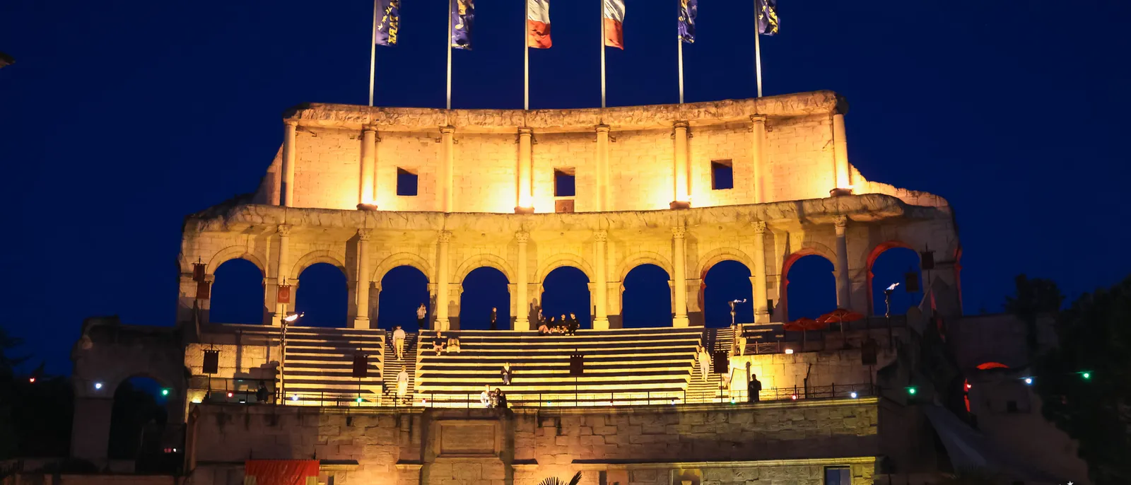 Hôtel Colosseo illuminé de nuit, réplique du Colisée surmontée de drapeaux, à Europa-Park