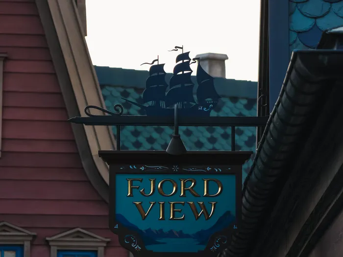Fjord View Shop sign lit up at dusk, with a sailing boat silhouette and a glowing street lamp