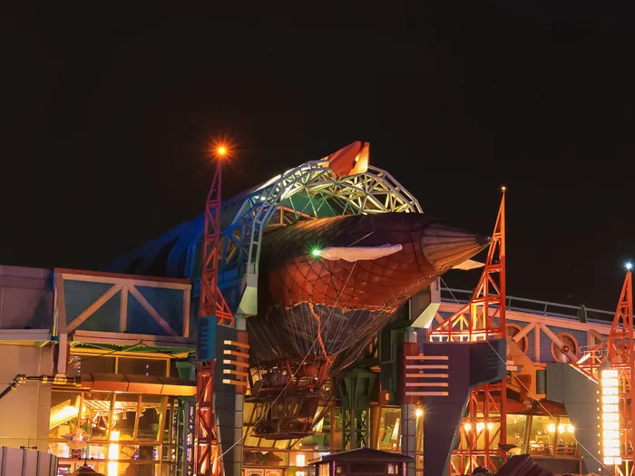 Le dirigeable Hyperion illuminé la nuit au-dessus du Café Hyperion, dans Discoveryland.