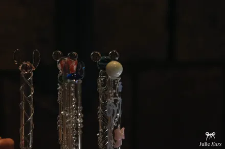 Trois baguettes magiques en verre personnalisées, aux embouts différents (oreilles, gemmes colorées, perle), fabriquées à Disneyland Paris.