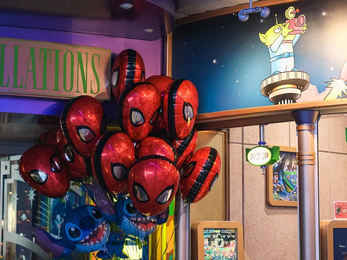 Spider-Man and Stitch balloons on sale in front of the photo spot’s space backdrop, at Disneyland Paris